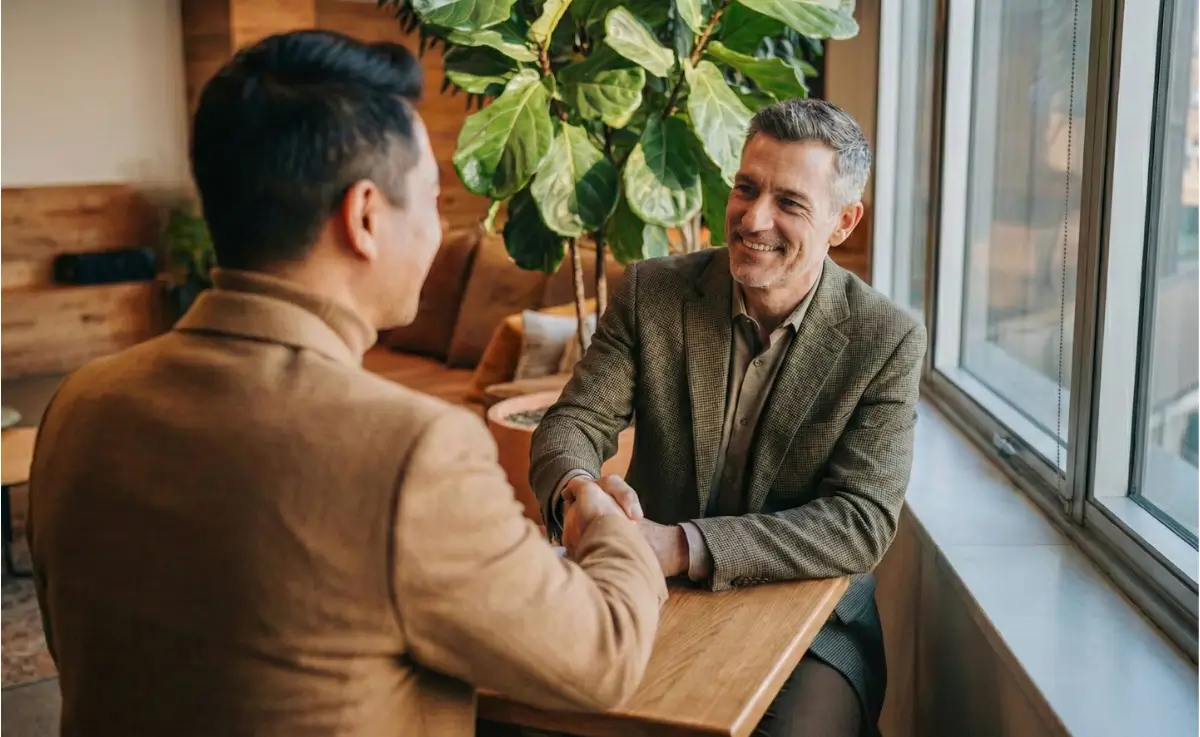Two real estate investment professionals shaking hands at a table